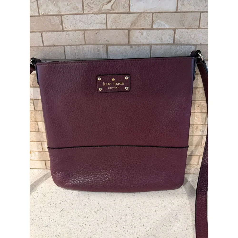 Kate Spade New York pebbled leather crossbody bag in a deep burgundy/wine color.